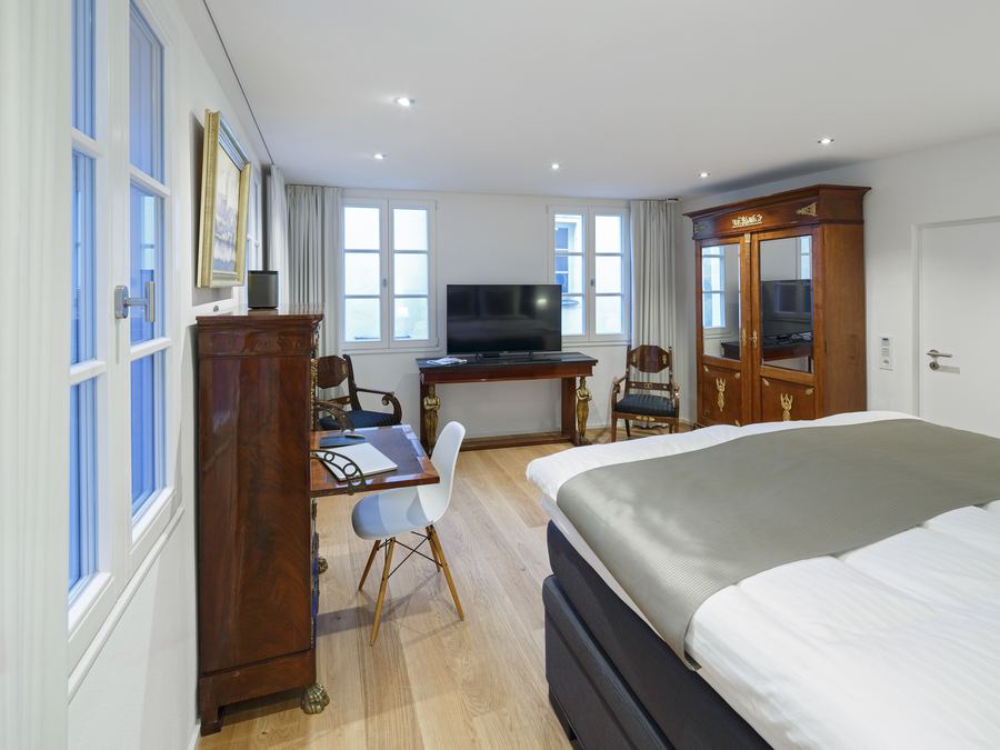 Schlafzimmer mit Fernseher und antiker Vitrine